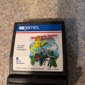 May include: A black rectangular video game cartridge for the Atari 2600. The label features a blue header with the text 'usgames.' and an illustration of a diver, a yellow octopus, and a shark. Text includes 'Name this Game and win $10,000'.