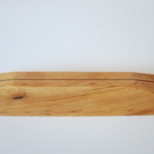 Op de afbeelding: Een houten displaystandaard met een natuurlijke afwerking. De standaard heeft een eenvoudig ontwerp met een verhoogd middengedeelte voor het presenteren van items.