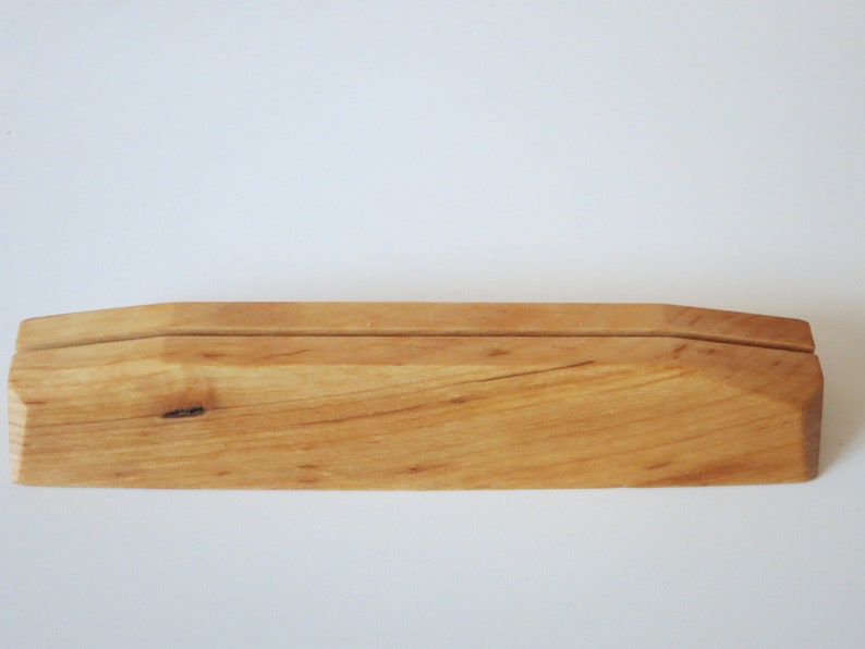 Op de afbeelding: Een houten displaystandaard met een natuurlijke afwerking. De standaard heeft een eenvoudig ontwerp met een verhoogd middengedeelte voor het presenteren van items.