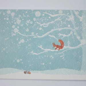 May include: A watercolour illustration of a red squirrel sitting on a snow-covered branch of a tree. The background is a light blue sky with white snowflakes.