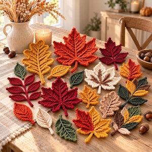 May include: A collection of crocheted leaves in various shapes and autumn colours, including shades of red, orange, yellow, green, and cream. The set features maple, oak, and compound leaf designs with visible yarn textures and intricate stitching.