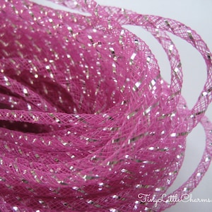 May include: Pink and silver metallic mesh ribbon. The ribbon is made of a fine mesh material with silver metallic threads woven throughout. The ribbon is coiled and ready to be used for crafting or decorating.