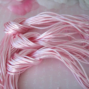 May include: A bundle of pink satin cord, a type of string used for jewelry making and crafts.