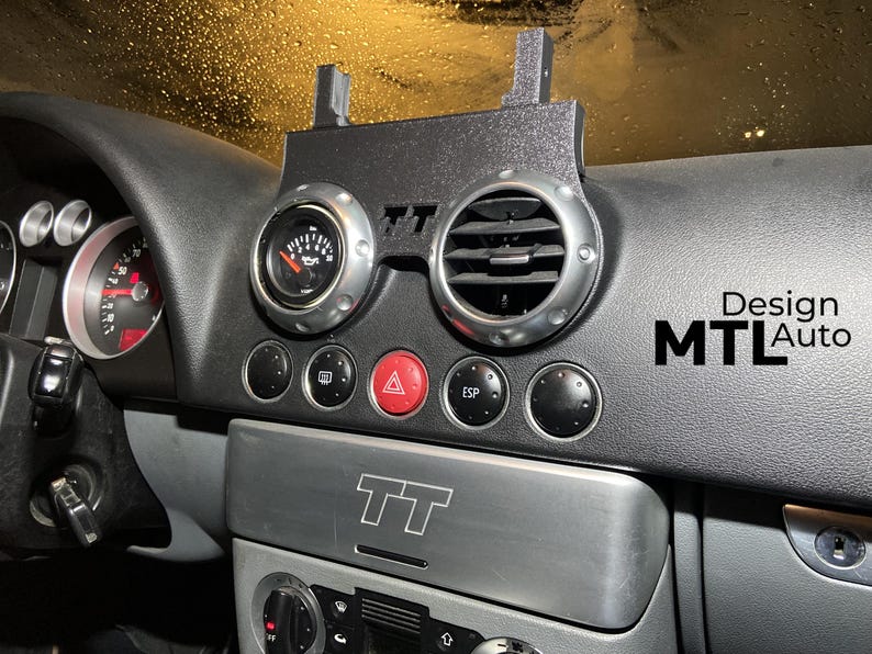 May include: Black dashboard with gauges, air vents, and buttons. A black mounting bracket is attached to the dashboard. The dashboard has the text "Design MTL Auto".