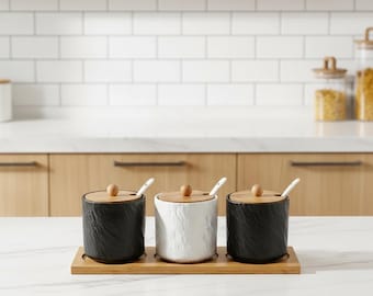 Juego de tarros de cerámica para condimentos en blanco y negro, tapas de madera, cucharas y bandeja.