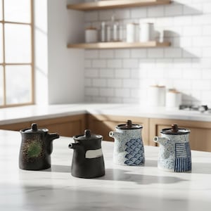 Puede incluir: Cuatro dispensadores de salsa de cerámica con tapas y boquillas marrones. Los dispensadores tienen diferentes diseños: negro y verde moteado, negro liso con una raya blanca, un diseño de olas azules y un diseño a rayas azules y blancas.