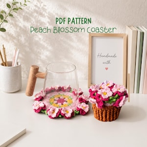 Pode incluir: Um porta-copos de crochê de flor de pêssego e um arranjo floral correspondente em uma pequena cesta. O porta-copos é rosa, verde e amarelo, com o texto "PDF PATTERN Peach Blossom Coaster".