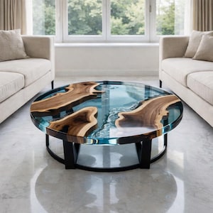 Pode incluir: Mesa de centro redonda com tampo de vidro transparente, apresentando secções de madeira natural e um design de rio de resina azul. A mesa tem uma base de metal preto.