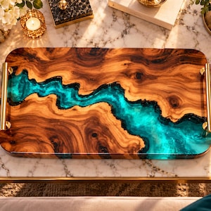 May include: A rectangular serving tray made of natural wood with a prominent, wavy river-like inlay of translucent turquoise resin running through the center. The tray features two polished gold-tone metal handles attached to the sides.