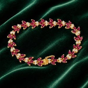 May include: A gold-toned bracelet featuring a repeating leaf-like pattern composed of marquise-cut deep pink stones and small, clear round stones. The design forms a continuous circular link chain with a secure metal clasp closure mechanism.