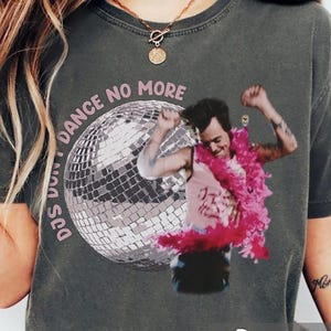 May include: A white ceramic mug with a black handle and the text "But First, Coffee" in a bold, black font. The mug is filled with a dark liquid, probably coffee, and rests on a light-coloured surface.