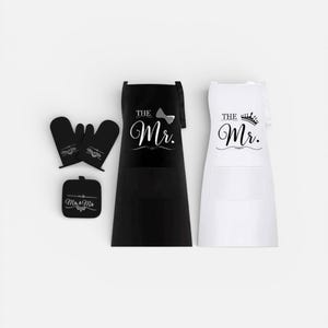 May include: A kitchen set featuring a black apron with "The Mr." and a bow tie, and a white apron with "The Mr." and a crown. Also includes oven mitts and a pot holder, all with white text on a black background.