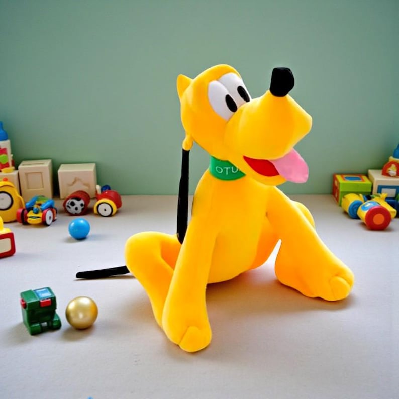 May include: A plush yellow dog with black ears and a black tail, wearing a green collar with the word "OTU". The dog has a pink tongue sticking out. Toys are scattered around the dog.