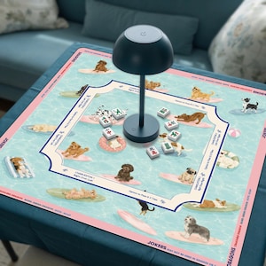 Peut inclure: Un tapis de mah-jong carré avec un motif d'eau bleu clair et divers chiens sur des planches de surf et des bouées. Le tapis inclut du texte sur les règles Charleston et les dragons. Une lampe champignon bleu foncé est posée au centre.