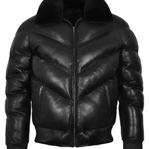 May include: A black leather puffer jacket with a plush, black fur collar. The jacket features a zip-up front, two side pockets, and ribbed cuffs and hem. The design includes a quilted pattern across the chest and sleeves.