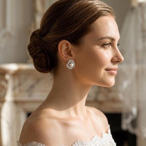 Elegant freshwater pearl bridal earrings worn by a bride with an updo hairstyle and white wedding dress.