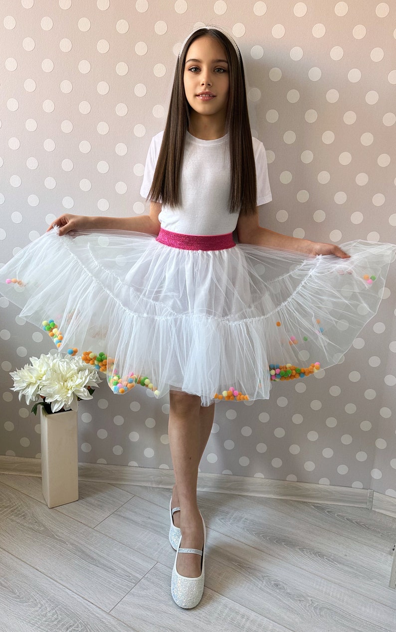 Whimsical Charm: Our handmade kids' skirt boasts delightful white pompoms for a playful touch of elegance!