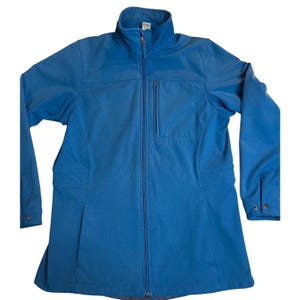 May include: A blue, full-zip jacket with a stand-up collar. The jacket features a vertical chest pocket, two side pockets, and buttoned cuffs. The jacket is made of a soft, flexible material.
