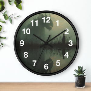 Puede incluir: Reloj de pared redondo con marco negro. La esfera del reloj presenta una escena oscura y atmosférica con una figura silueteada y una criatura reflejada en el agua. Los números blancos marcan las horas.