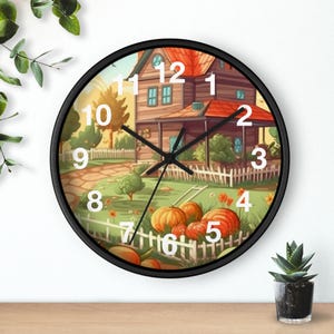 Puede incluir: Un reloj de pared redondo con marco negro. La esfera del reloj presenta una colorida ilustración de una casa, calabazas y una valla blanca. Las manecillas del reloj son negras y los números blancos. Medidas en centímetros.
