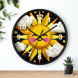May include: A round wall clock with a black frame. The clock face features a smiling yellow sun with pink cheeks, white clouds, and white numbers. The background is black with small stars.