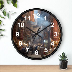 Könnte beinhalten: Runde Wanduhr mit schwarzem Rahmen. Das Zifferblatt zeigt eine belebte Straßenszene mit weißen Ziffern und schwarzen Zeigern. Der Hintergrund zeigt einen geschäftigen Markt mit Menschen und Ständen.