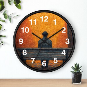 May include: Black-framed wall clock featuring a painting of a person sitting on a bench, with an orange and yellow background. White numerals mark the hours. The clock hands are black.