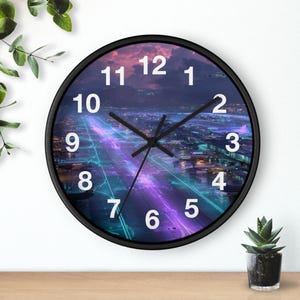 May include: A round wall clock with a black frame. The clock face features a futuristic cityscape in shades of purple, blue, and pink. White numerals mark the hours, and black hands indicate the time.