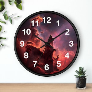May include: A round wall clock with a black frame. The clock face features a vibrant nebula design in shades of red, purple, and orange. White numerals mark the hours, and black hands indicate the time.