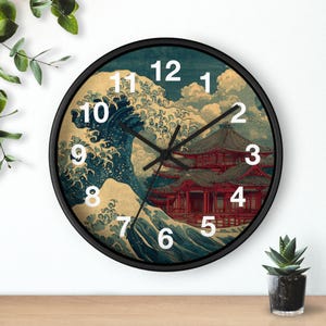 May include: A round wall clock with a black frame. The clock face features a Japanese-style wave and mountain scene with a red pagoda. White numerals mark the hours, and black hands indicate the time.
