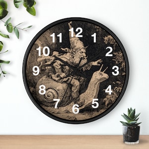 May include: A black wall clock with a sepia-toned illustration of a gnome riding a snail. The clock face has white numerals and black clock hands. The clock is round with a black frame and is displayed on a wooden surface.