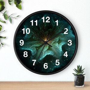 Könnte beinhalten: Eine runde Wanduhr mit schwarzem Rahmen. Das Zifferblatt zeigt ein abstraktes Design in Türkis und Gold mit weißen Ziffern. Die Zeiger der Uhr sind schwarz.