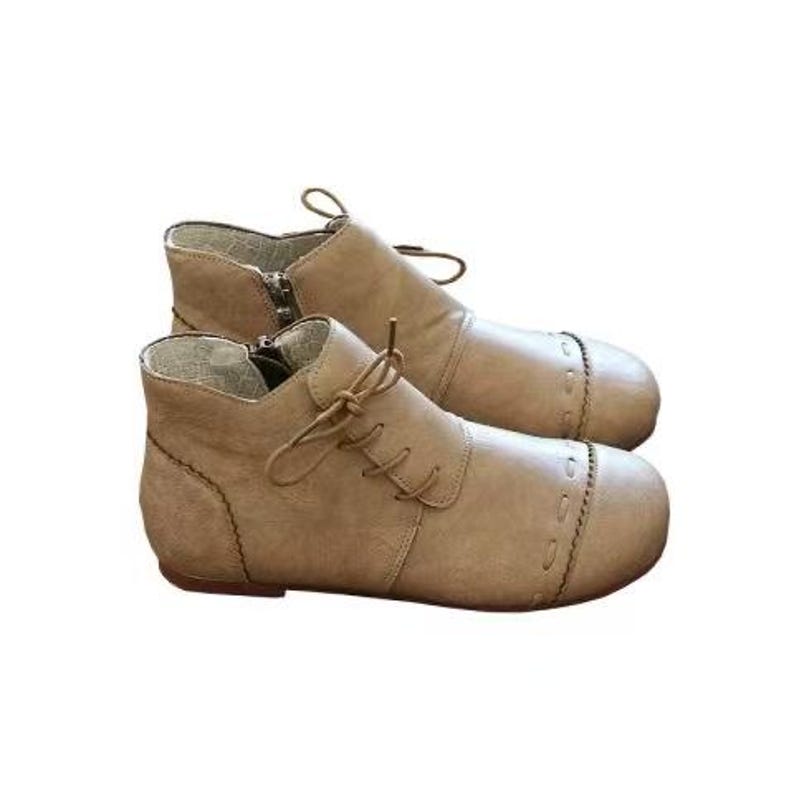 May include: A pair of tan ankle boots with laces and a side zipper. The boots have a rounded toe and decorative stitching along the seams. The boots are made of a soft, leather-like material.
