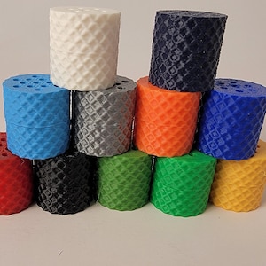 May include: A collection of colorful, cylindrical objects with a textured, diamond-patterned surface. The objects are stacked in a pyramid shape, showcasing a variety of colors including red, black, green, yellow, blue, orange, gray, and white. The objects appear to be 3D printed.