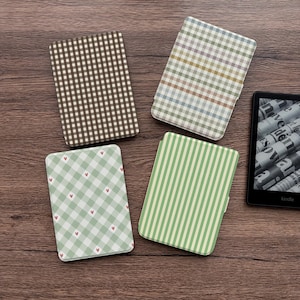 May include: Four rectangular e-reader cases featuring distinct patterns: one with a brown and white gingham check, one with a multicolored plaid, one with a light green gingham check and small red hearts, and one with green and white vertical stripes.
