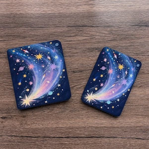 May include: Two rectangular covers featuring a dark blue space-themed design with a swirling nebula, bright yellow and pink stars, and small planets. The artwork displays a vibrant cosmic trail of light stretching across the dark background.