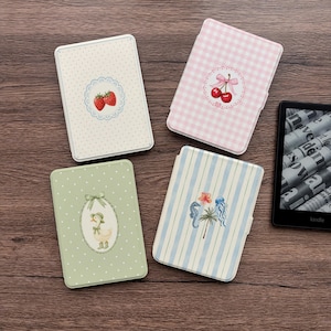 Può includere: Quattro custodie rettangolari per e-reader con motivi distinti: una custodia color crema a pois con fragole, una custodia rosa a quadretti con ciliegie, una custodia verde a pois con un'anatra e una custodia a righe blu con vita marina.