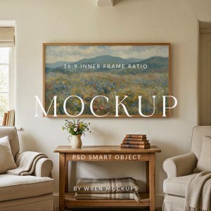 May include: A mockup image featuring a framed landscape painting with a wooden frame, hanging above a wooden table. The table holds a vase of flowers, books, and a folded blanket. The text "MOCKUP" is displayed prominently.