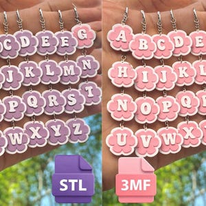 Puede incluir: Llaveros del alfabeto en dos combinaciones de colores: morado y rosa. Cada llavero presenta una letra de la A a la Z en fuente blanca, sobre un fondo en forma de flor. Los llaveros están sujetos a cadenas plateadas.