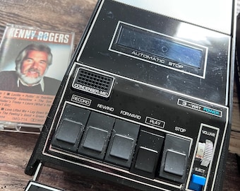 Grabadora de casetes portátil GE M8445A en funcionamiento, reproductor de audio analógico retro, estuche original.