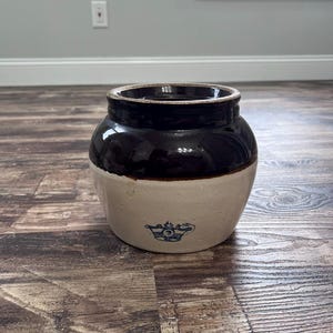 May include: A two-toned stoneware crock featuring a dark brown glazed upper section and a light beige lower body. The front of the vessel displays a blue stamped crown logo with the number 3 centered inside, indicating its capacity or size.