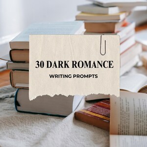 May include: A stack of books with a paper attached by a paper clip that reads "30 DARK ROMANCE WRITING PROMPTS". Several other books are visible in the background, some open, on a white surface.
