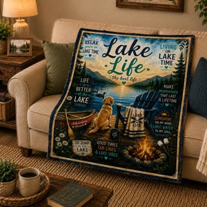 May include: A rectangular throw blanket featuring a scenic lake landscape with a golden retriever, a wooden boat, a blue chair, and a campfire. The text reads Lake Life, the best life, Relax you're on lake time, and other lake-themed phrases.