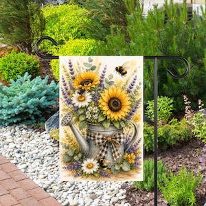 May include: A rectangular garden flag featuring a watercolor illustration of a galvanized metal watering can filled with yellow sunflowers, white daisies, and purple lavender sprigs. A black and white gingham bow is tied to the handle.