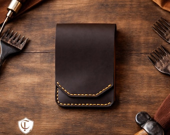 May include: A dark brown leather wallet with yellow stitching. The wallet is rectangular with a flap closure. The Craftline Leather logo is visible in the lower left corner. Tools are arranged around the wallet on a wooden surface.