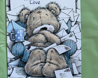 May include: Greeting card with a teddy bear illustration. The bear is surrounded by envelopes and a blue mug. The text "For You, Grandson With Love" is written at the top of the card. The card has a white border and is on a green surface.