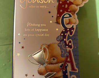 May include: Birthday card for a godson with a teddy bear holding a trophy. The card reads "Happy Birthday to a Godson who is very... Wishing you lots of happiness on your special day."