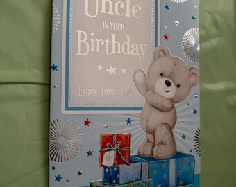 May include: A birthday card for an uncle, featuring a gray teddy bear waving from atop a stack of wrapped gifts. The card has a light blue background with silver accents and the text "FOR A DEAR Uncle ON YOUR Birthday".