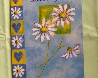 May include: Greeting card with the word "Granddaughter" in script. The card features a blue background with daisies and a decorative border of hearts and flowers. The daisies have white petals and yellow centers.