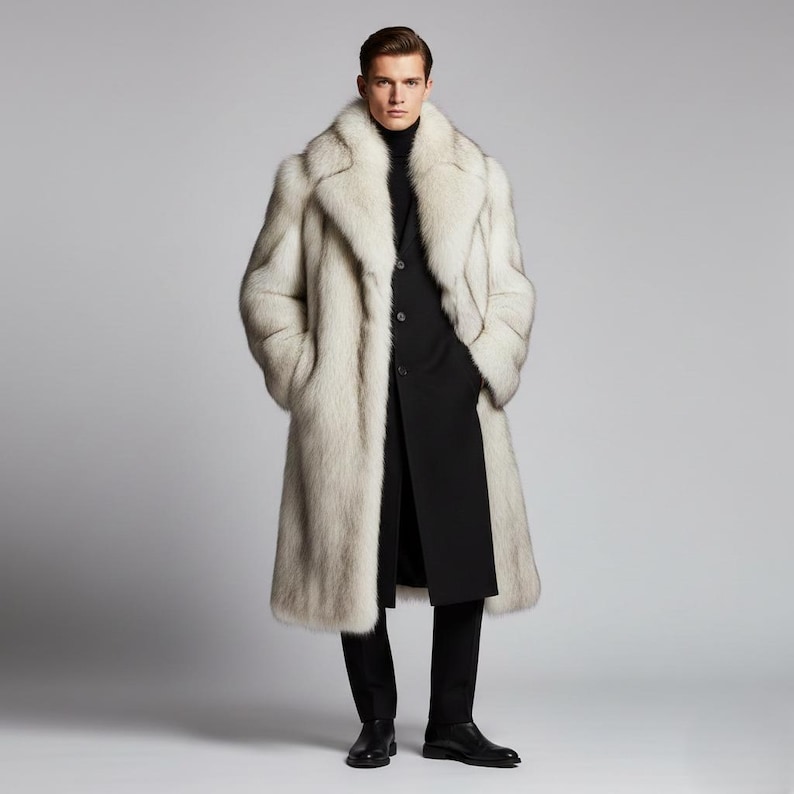 May include: A full-length, light-colored fur coat with a wide collar. The coat is worn over a black suit with a turtleneck. The model is wearing black dress shoes. The background is a solid gray.